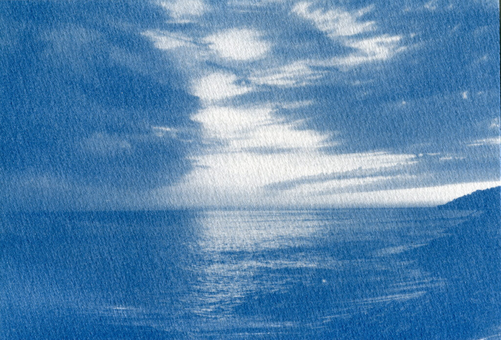 Cyanotype. Coucher de soleil sur l'océan avec un ciel chargé et une mer d'huile.